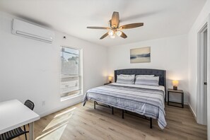 A bedroom with a bed, bedside tables, a desk, and a chair. - Pet-Friendly Montrose 1BR | Museum District | Free Parking<br>newly renovated (Houston)