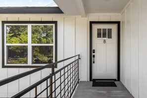 A white door with a number 8, a black metal railing, and a window with blinds. - Pet-Friendly Montrose 1BR | Museum District | Free Parking<br>newly renovated (Houston)