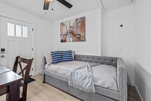 Ein modernes Wohnzimmer mit einem grauen Sofa, gestreiften Kissen und einem Gemälde einer Kanalansicht.
