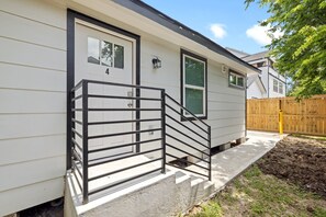 Einbungalow mit einer Veranda, einer Metalltreppe und einem Holzzaun im Hintergrund.