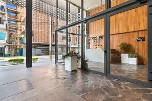 A modern hotel entrance with stone flooring, glass doors, and wooden paneling. - Stylish studio close to beach restaurants and clubs (Puerto Vallarta)