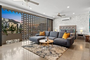 A modern living room with a grey sofa, a round coffee table, and a view of the cityscape through large windows. - Stylish studio close to beach restaurants and clubs (Puerto Vallarta)