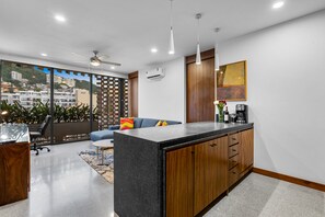 Une cuisine moderne dotée d’un îlot central, de meubles en bois et offrant une vue sur le paysage urbain grâce à de grandes fenêtres.