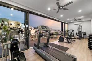Une salle de sport moderne dotée de divers équipements d’exercice, de grandes fenêtres et offrant une vue sur le paysage urbain.