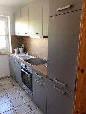 Eine Küche mit grauen Schränken, einer Edelstahl-Spüle und einem eingebauten Backofen.