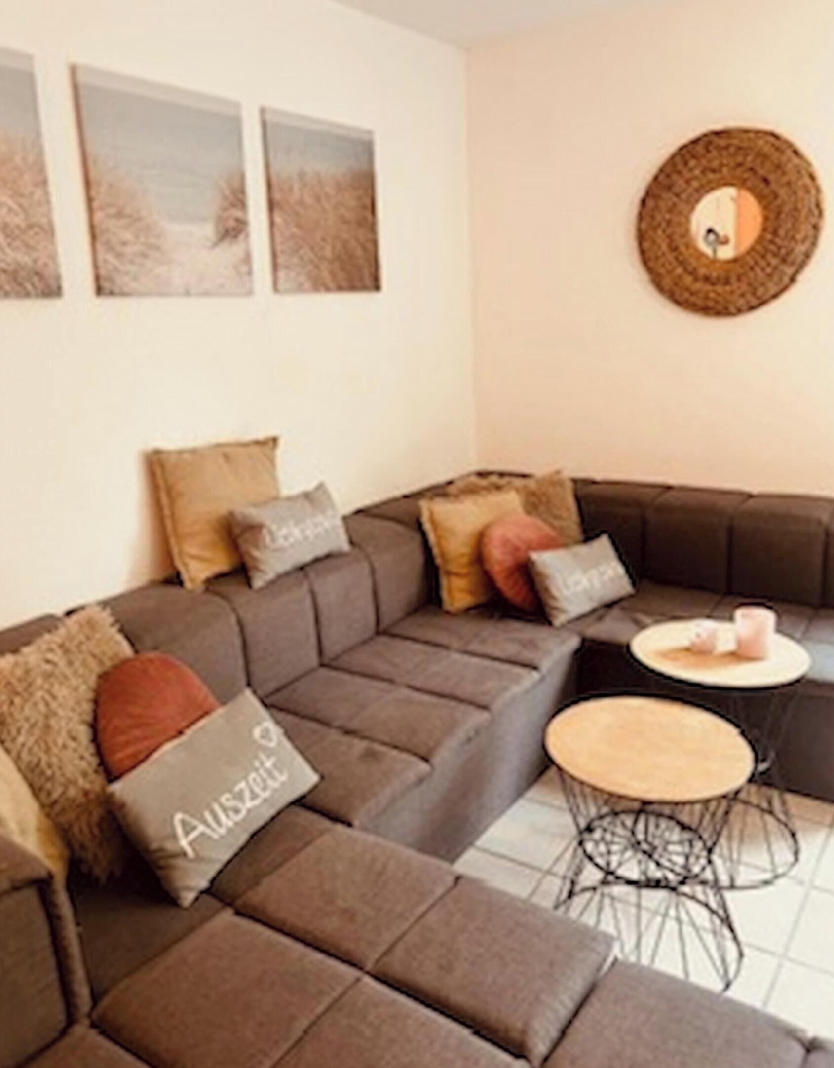 Een moderne woonkamer met een modulaire bank, een ronde salontafel en een klein bijzettafeltje.