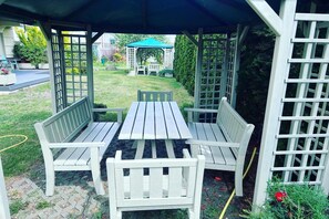Un espacio de estar al aire libre cubierto, con una mesa y bancos.