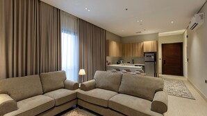 Een moderne woonkamer met een hoekbank, een eettafel en een keuken op de achtergrond.