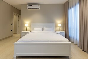 A hotel room with a large bed, bedside lamps, an air conditioner, and a view of the outside through a window with curtains. - Timeless Elegance And Comfort Redefined (Madinah)