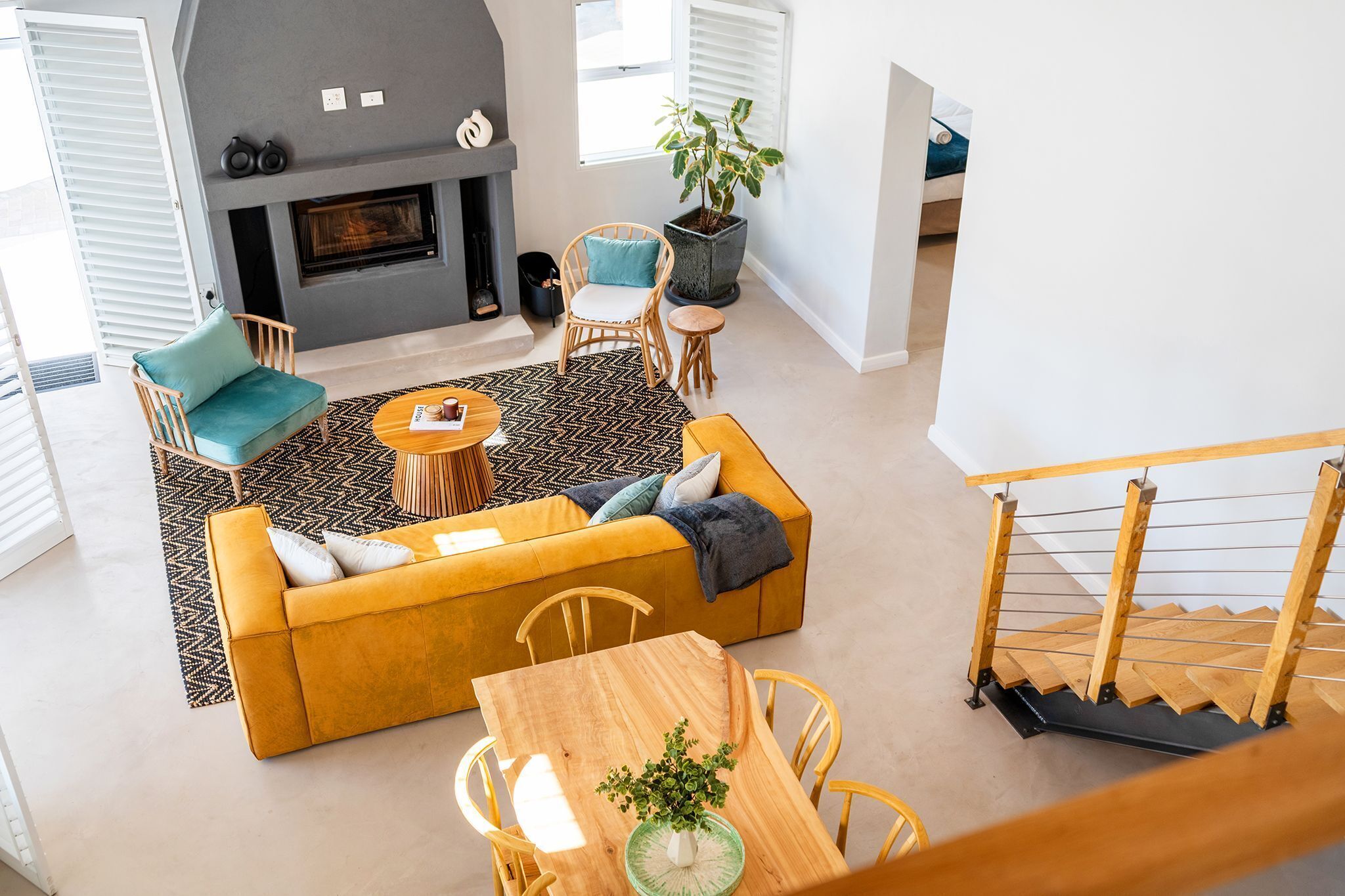 A living room with a sofa, chairs, a coffee table, a fireplace, and a staircase.