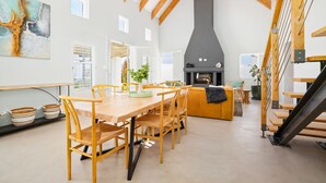 Un comedor espacioso con una mesa y sillas de madera, una chimenea y una escalera.