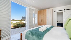 Un dormitorio con cama, armario de madera, baño con ducha y vistas al exterior.