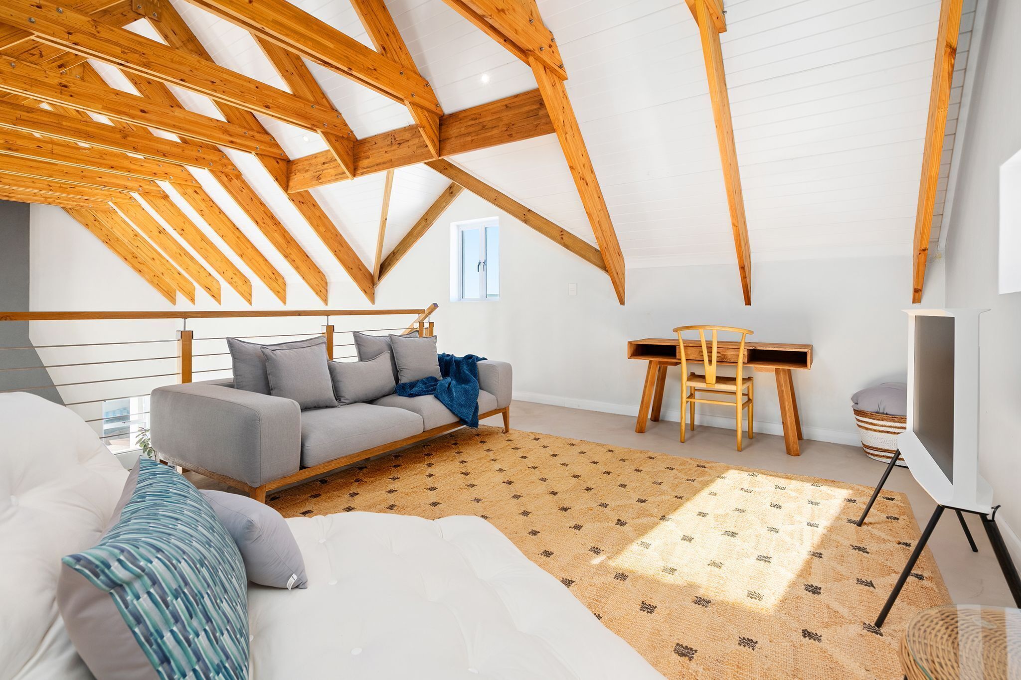 A room with a sloped ceiling, a sofa, a small table, and a TV.
