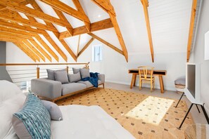 A room with a sloped ceiling, a sofa, a small table, and a TV.