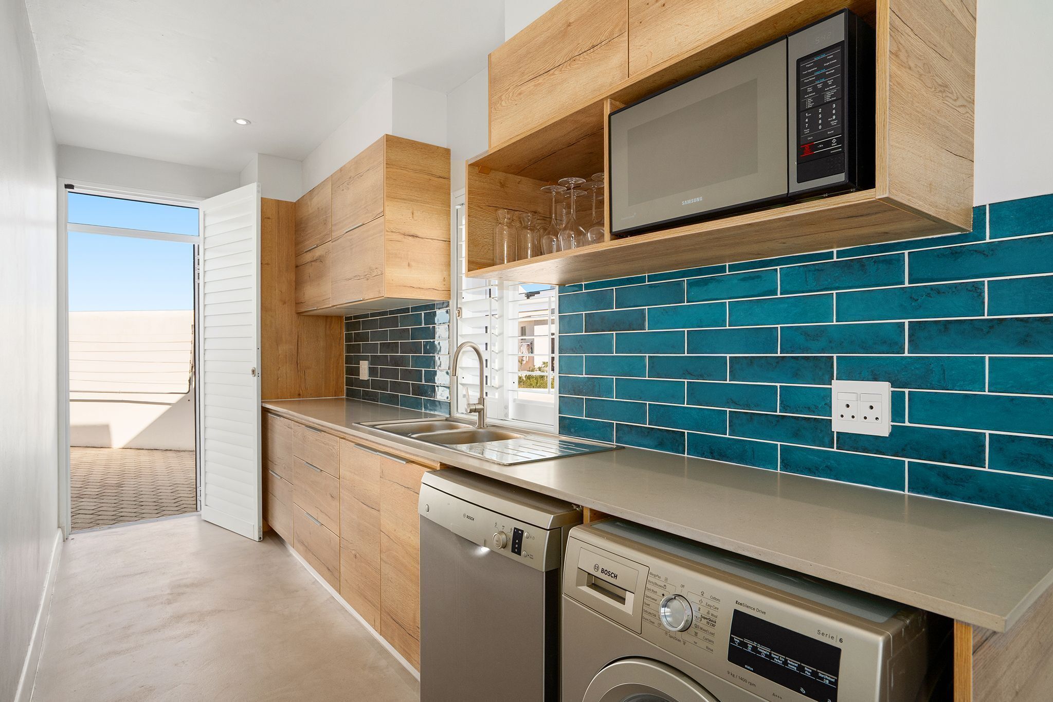 A modern kitchen with wooden cabinets, a dishwasher, a microwave, and a sink.