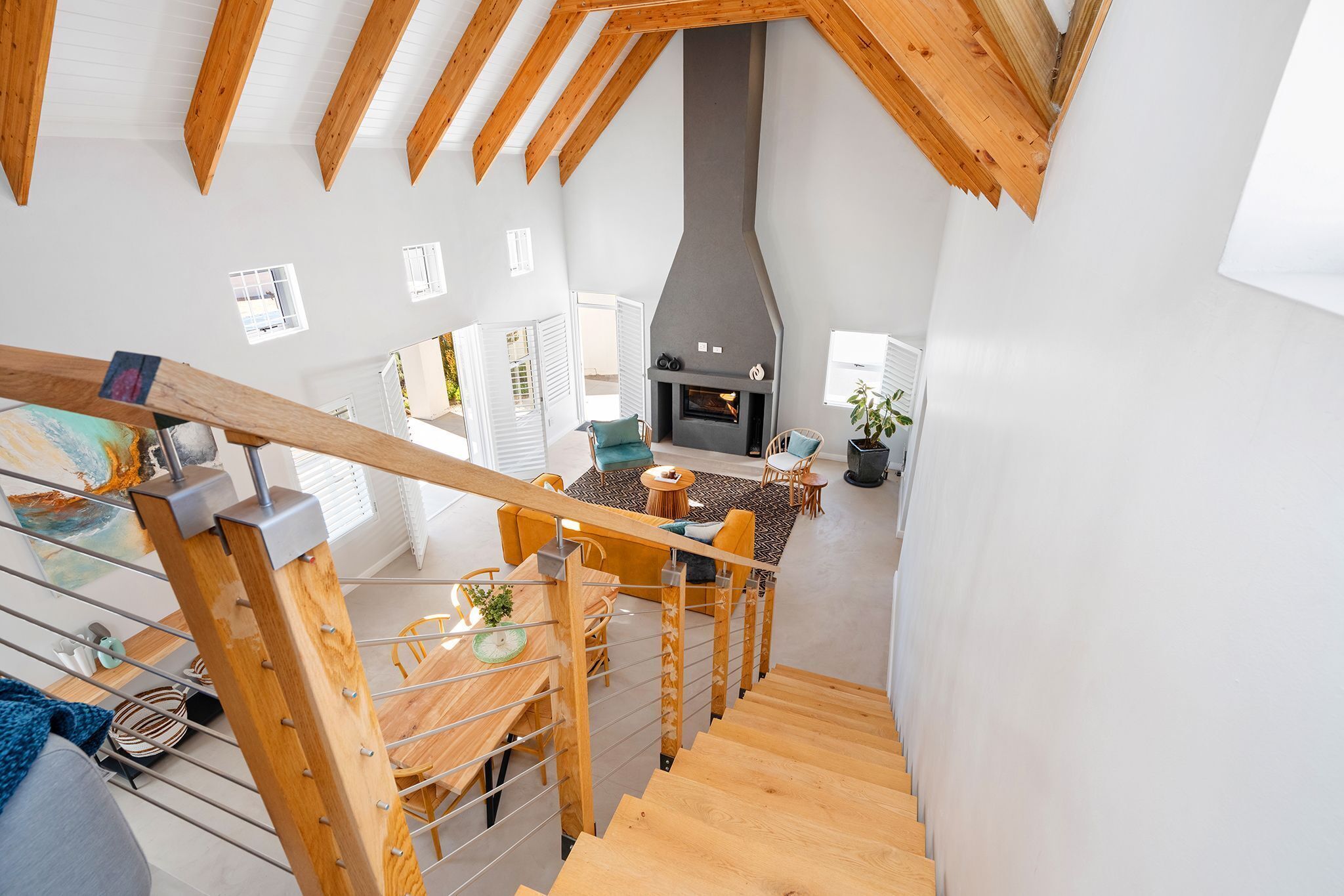 Un interior moderno con una escalera de madera, una chimenea y un comedor.
