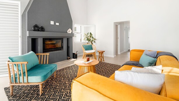Una sala de estar moderna con chimenea, un sofá, una silla y una mesa de centro.