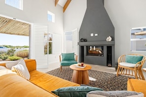 A modern living room with a fireplace, a sofa, chairs, and a patterned rug.