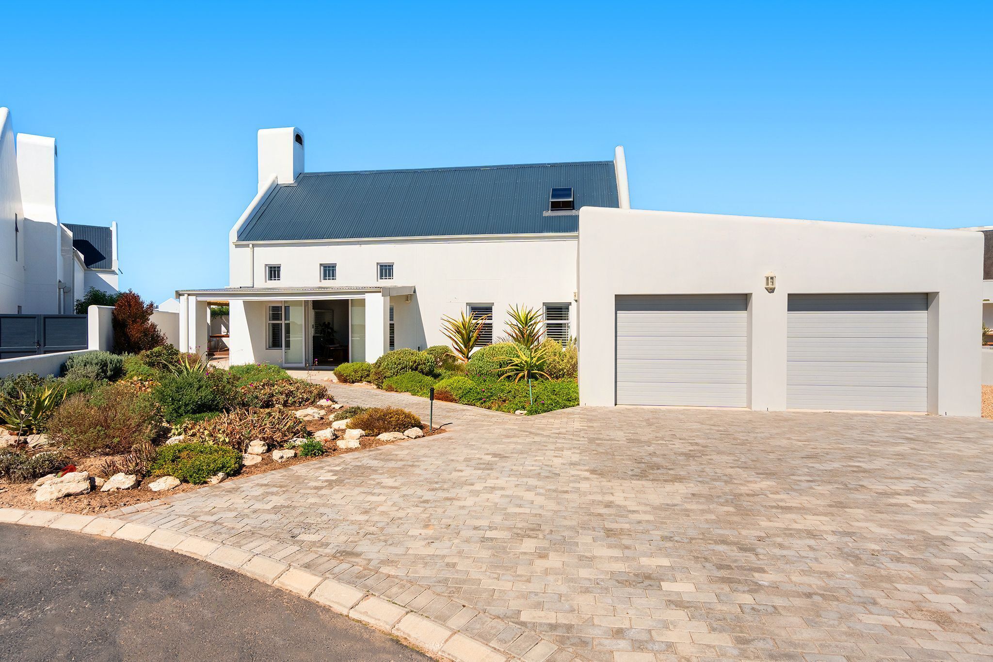 A modern house with a paved driveway, garage doors, and a well-maintained garden.