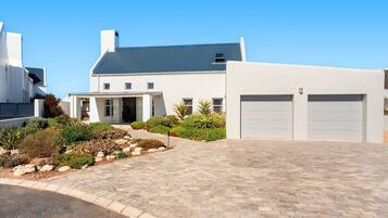 A modern house with a paved driveway, garage doors, and a well-maintained garden.