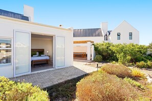 A modern house with a glass door leading to a bedroom with a bed and a bench.