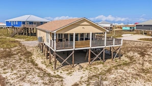 A beachfront house with a balcony, wooden deck, and a covered porch. - Mac's Crab Shack | Ocean Views | Great Location (Dauphin Island)