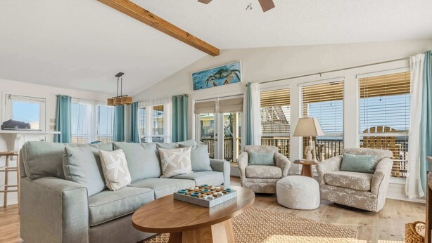 A living room with a grey sofa, two armchairs, a coffee table, and a view of the outside. - Mac's Crab Shack | Ocean Views | Great Location (Dauphin Island)