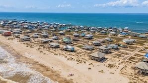 A coastal resort with beachfront cottages, a pier, and a sandy beach. - Mac's Crab Shack | Ocean Views | Great Location (Dauphin Island)