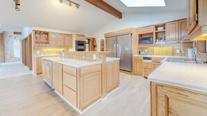Una cocina amplia con armarios de madera, una isla central, un refrigerador de acero inoxidable y un tragaluz.