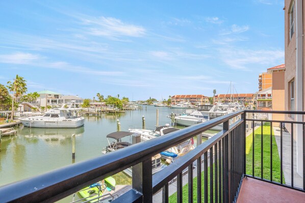 A marina with boats docked, a clear sky, and buildings in the background. - Madeira Bay Resort #204 – Marina Views & Steps to the Beach (Madeira Beach)