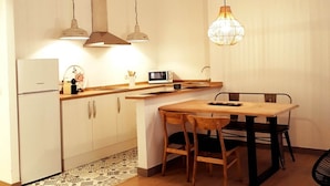 Cocina compacta con comedor, que incluye refrigerador, microondas y mesa de madera con sillas.