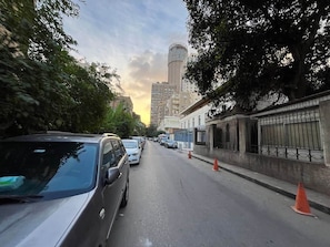A street with parked cars, trees, and buildings. - The Greenhouse | Zamalek (Cairo Governorate)