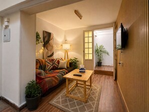 Ein gemütliches Wohnzimmer mit einer Couch, einem Couchtisch und einem an der Wand montierten Fernseher.