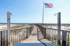 A wooden boardwalk leading to a beach with an American flag. - 2BR Beach Condo, Shared Pool, Tennis Courts (Gulf Shores)