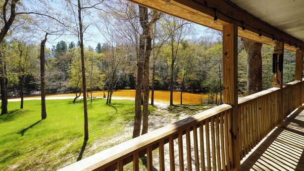 A wooden deck with a view of a river and forest.