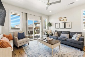A living room with a sofa, armchair, coffee table, and a ceiling fan.