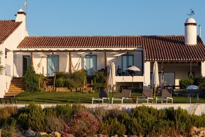 A two-story house with a tiled roof, a covered patio with outdoor seating, and a landscaped garden.