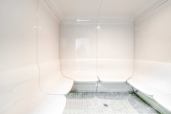 A sauna room with tiled flooring and benches. - Gulf-view condo with central AC, WiFi, laundry, pools, gym & tennis (Orange Beach)