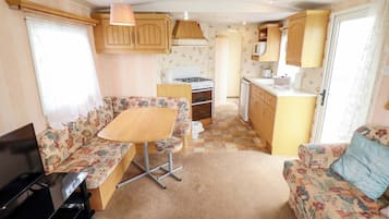 Interior compacto de una caravana con kitchenette, zona de comedor y espacio para sentarse.