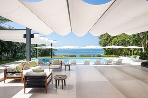 A poolside area with lounge chairs, umbrellas, and a view of the ocean. - Estate Buho in Punta Mita (Punta de Mita)