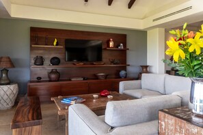A living room with a flat-screen TV, wooden shelves, a coffee table, and a sofa. - Penthouse Vista Encanto (Punta de Mita)