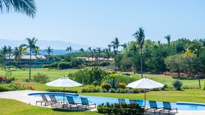 A pool area with lounge chairs and umbrellas, surrounded by lush greenery and palm trees. - Condo Zazil in Punta Mita (Punta de Mita)
