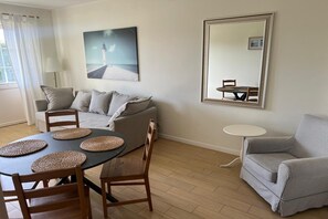 A dining area with a table, chairs, a sofa, and a mirror. - Large, Comfortable Apartment With a Terrace (Krokowa)