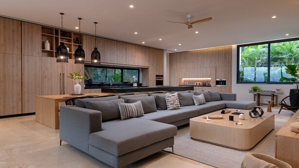 Una sala moderna con un sofá seccional, una mesa de centro de madera y un televisor.
