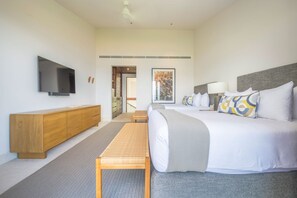 Ein Hotelzimmer mit einem großen Bett, einer Holzbank, einem Flachbildfernseher, einem Schreibtisch und einem Bild an der Wand.