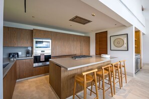 Eine moderne Küche mit Holzausstattung, einer zentralen Kochinsel mit Hockern, einem Einbauofen und einer Mikrowelle.