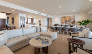 A modern living room with a sectional sofa, a round coffee table, and a dining area with a large painting. - Condo N Utica in Punta Mita (Punta de Mita)
