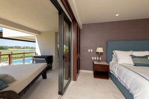 Une chambre à coucher comprenant un lit, une table de chevet, une lampe, une porte-fenêtre coulissante et une vue sur une piscine.