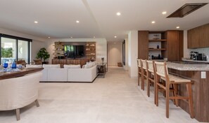 Une cuisine moderne dotée d’un îlot central, de meubles en bois et d’un coin repas avec des tabourets de bar.