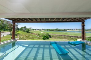 Une piscine à débordement offrant une vue sur un terrain de golf et un plan d’eau.